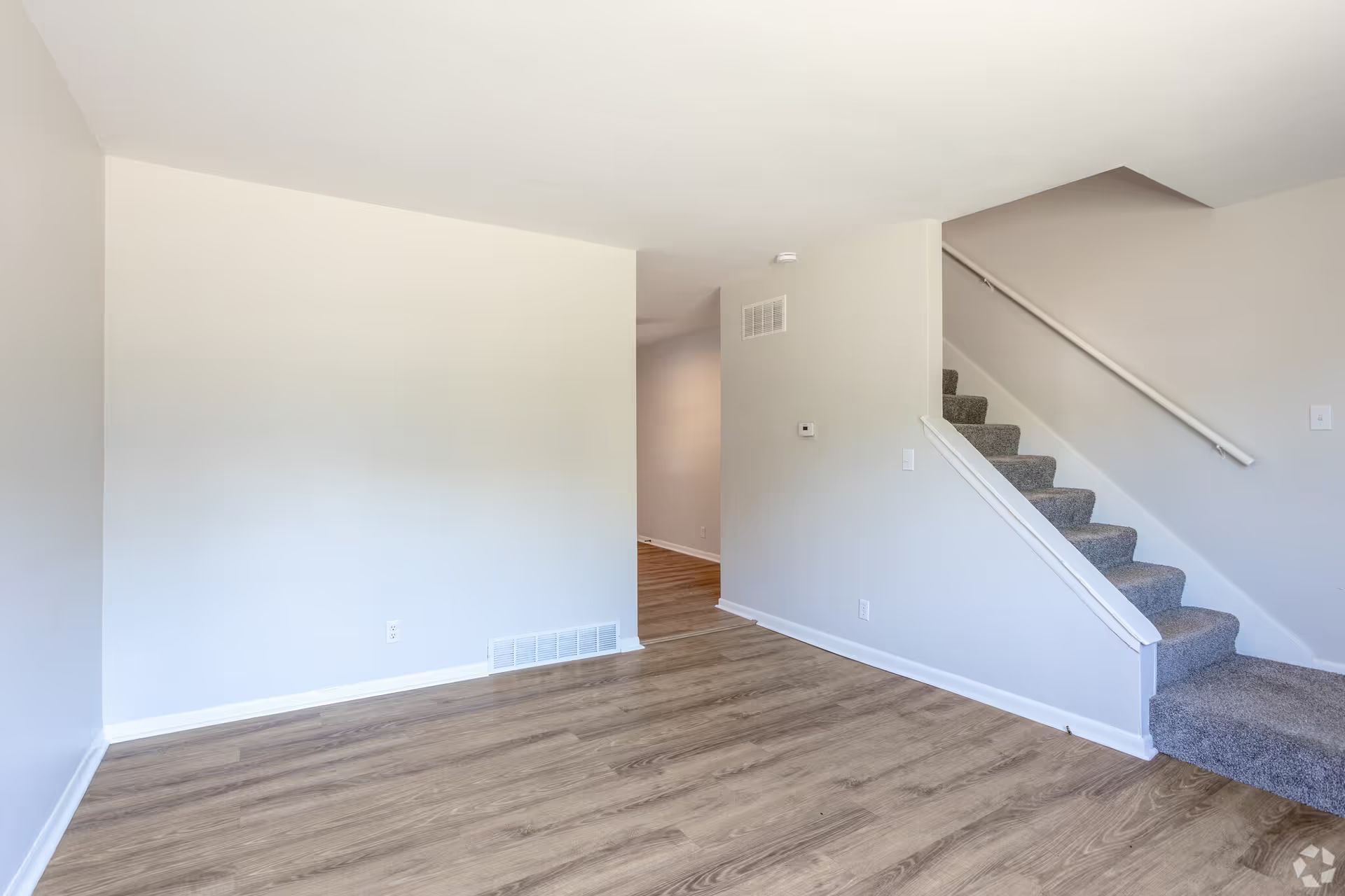 An empty living room with hardwood floors and stairs.