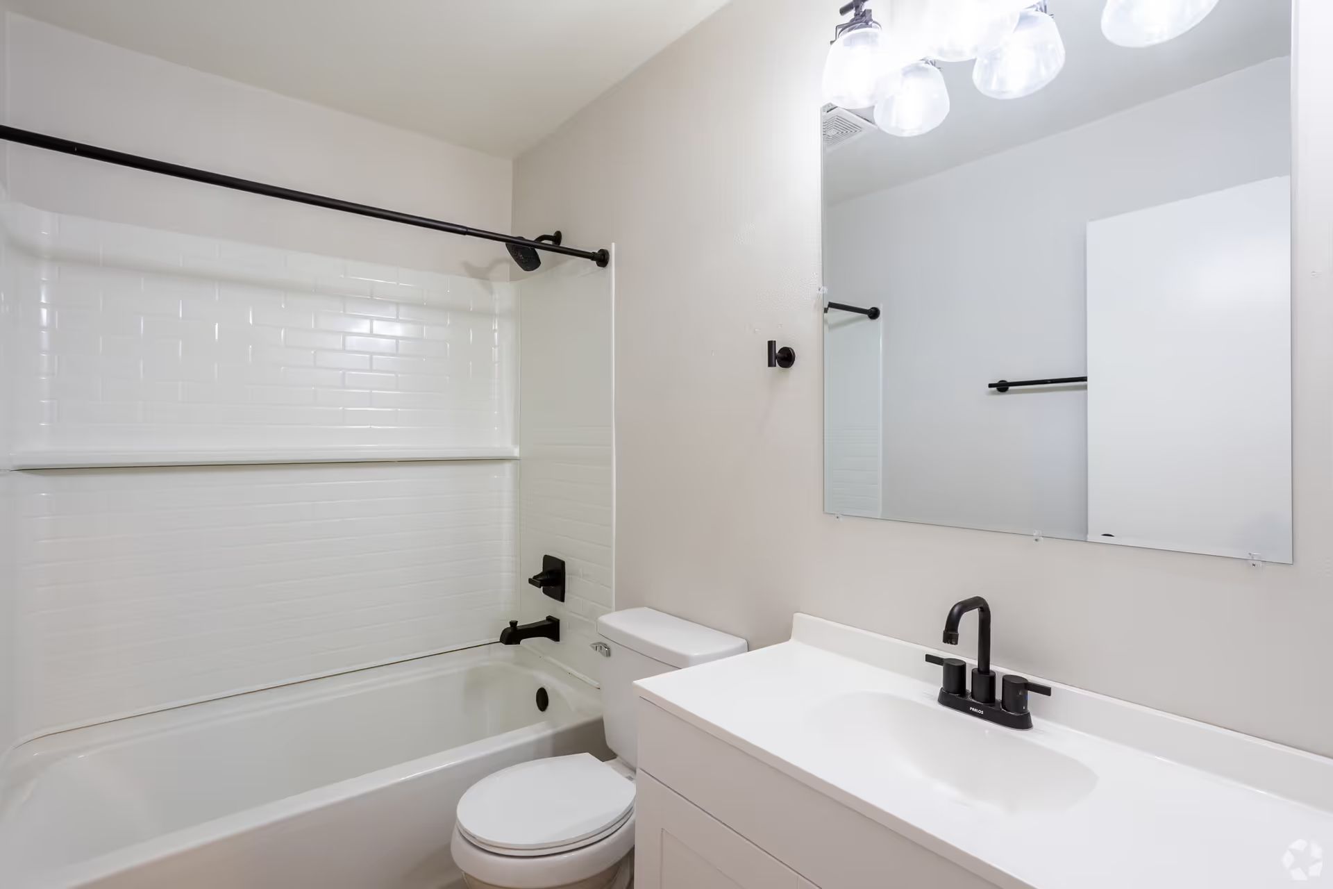 A bathroom with a toilet , sink , bathtub and mirror.