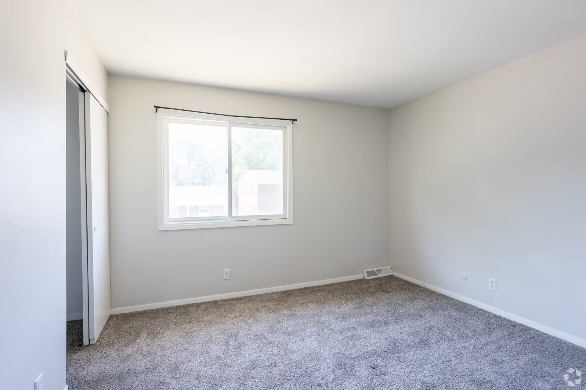 An empty bedroom with a window and a sliding glass door.