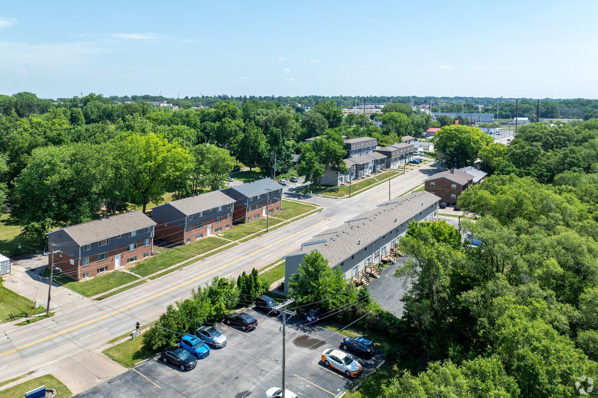 An aerial view of a residential area with a parking lot and trees.