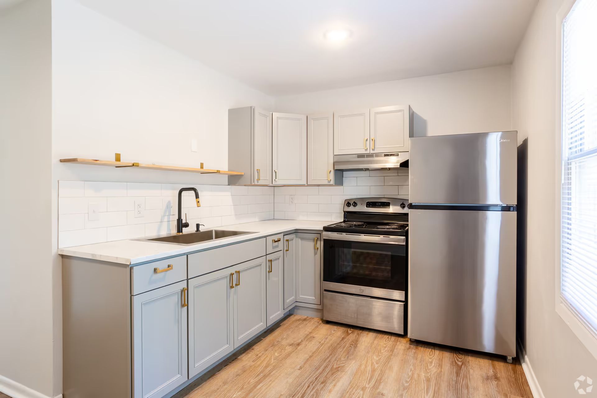 A kitchen with stainless steel appliances , gray cabinets , a sink , and a refrigerator.