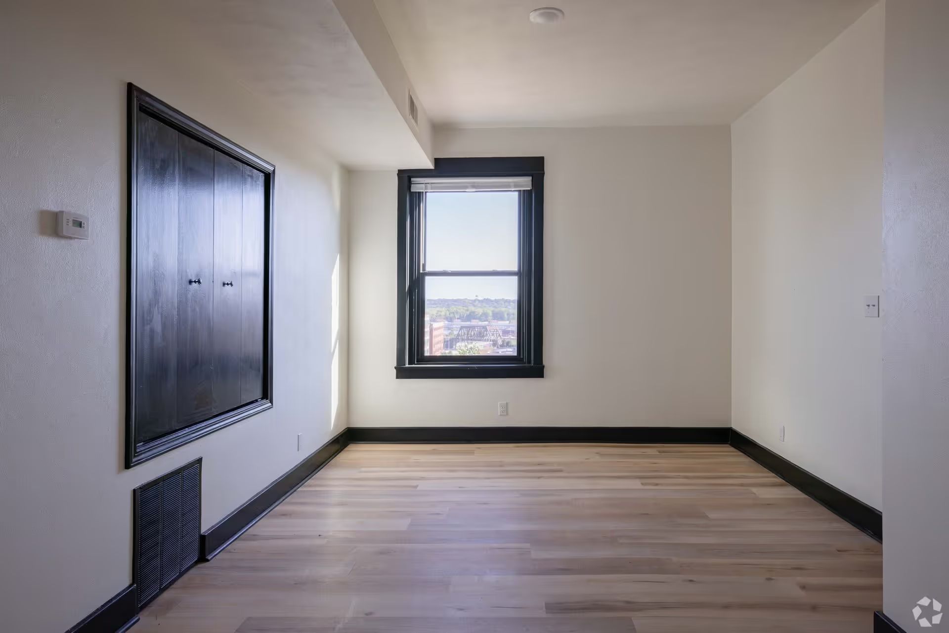 An empty room with hardwood floors and a window.