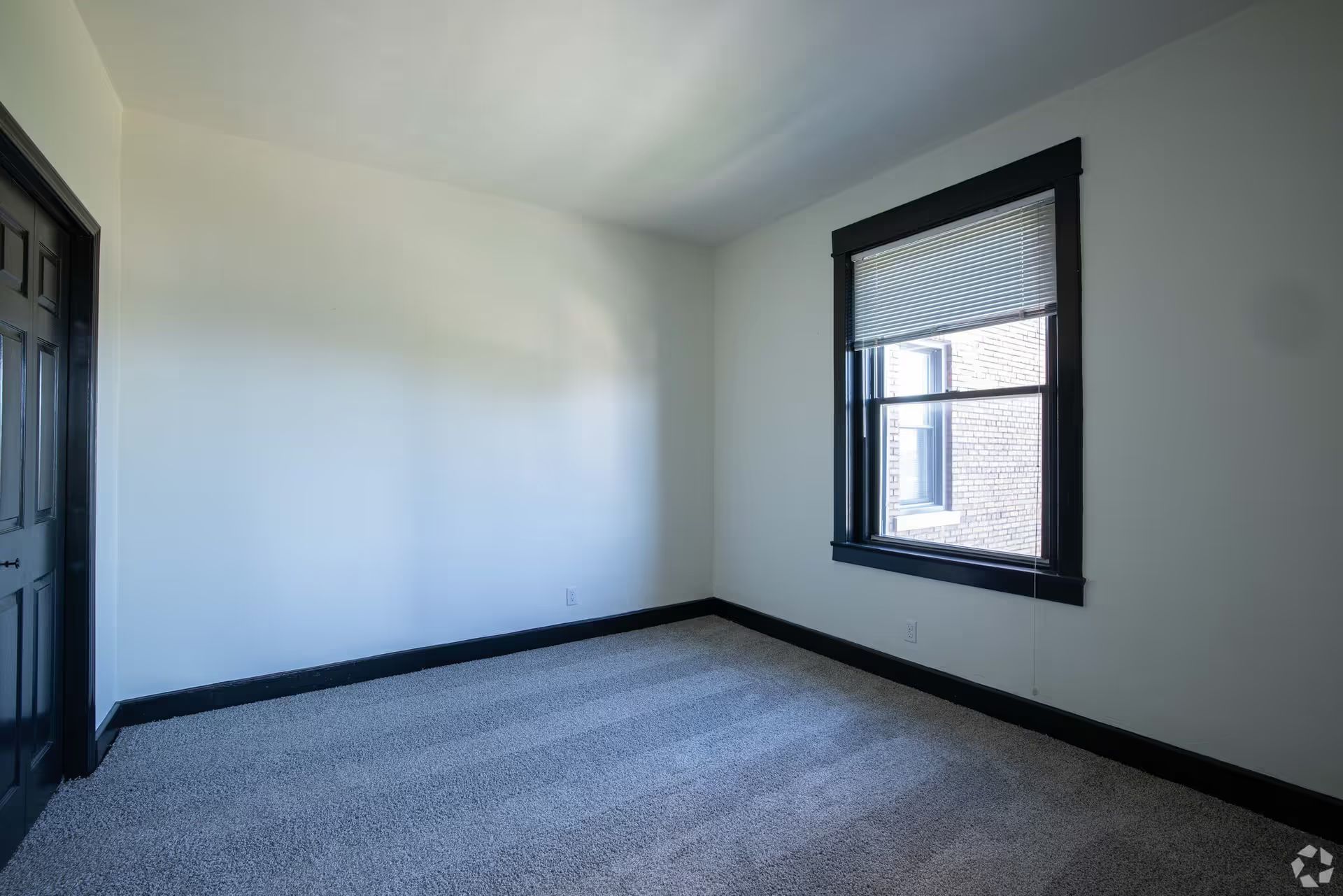 An empty bedroom with a window and carpet.