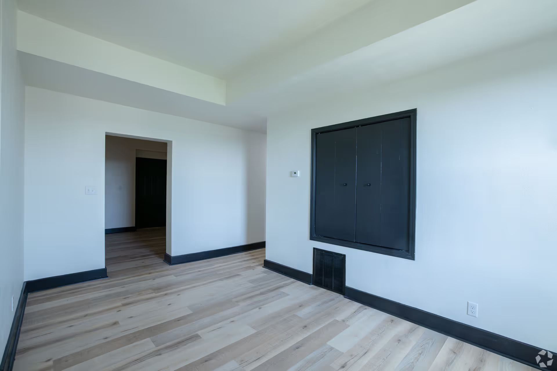 An empty room with hardwood floors and white walls.