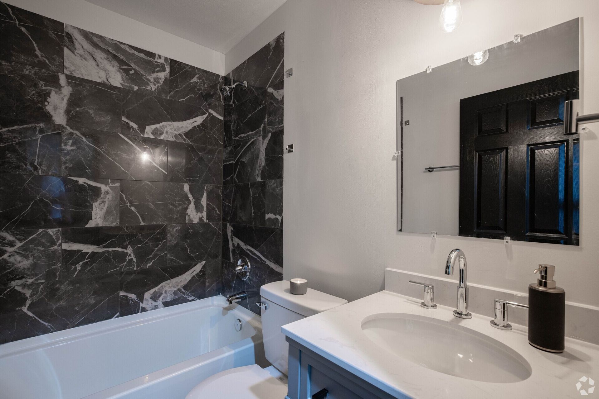 A bathroom with a sink , toilet , bathtub and mirror.