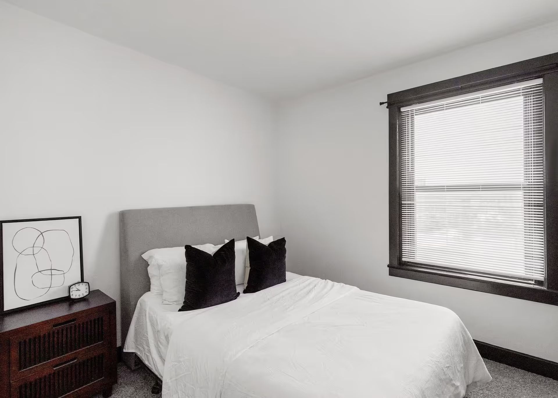 A bedroom with a bed , nightstand , and window.