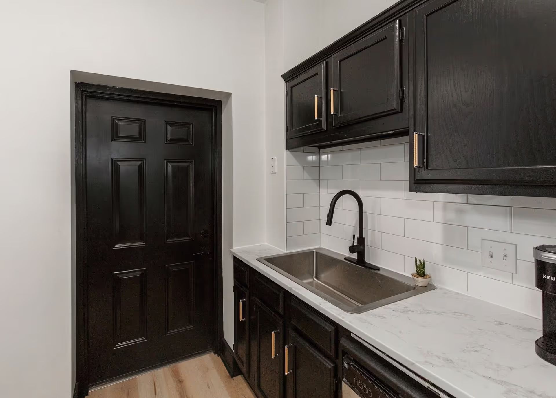 A kitchen with black cabinets , a sink , and a dishwasher.