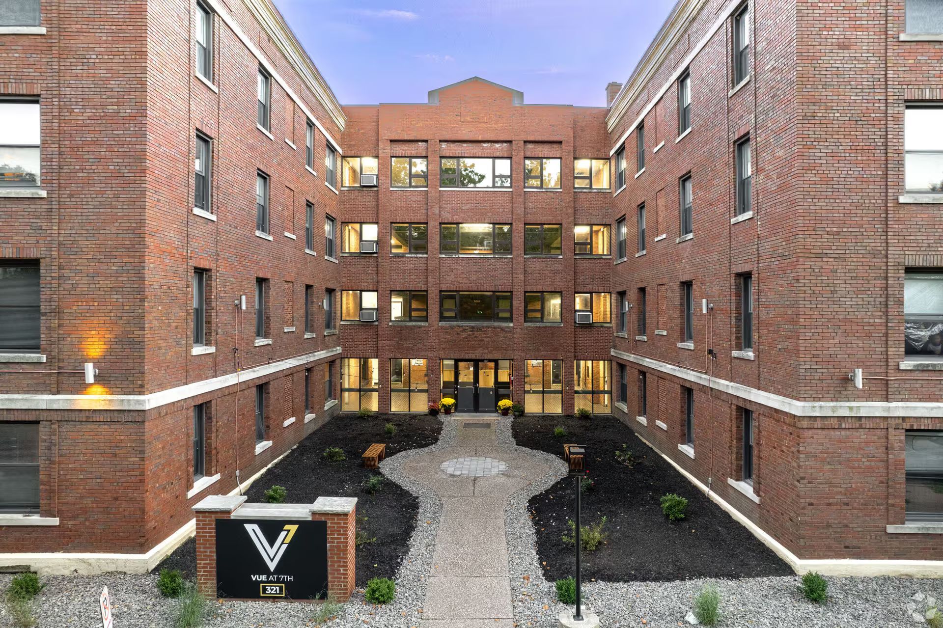 A large brick building with a courtyard in front of it.