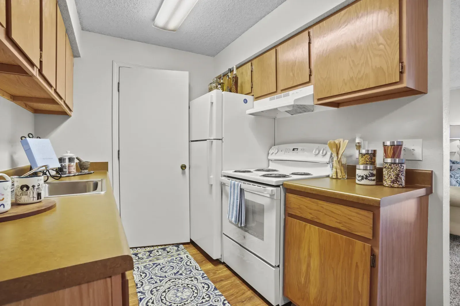 View of a kitchen with wooden cabinets, stove, and refrigerator.