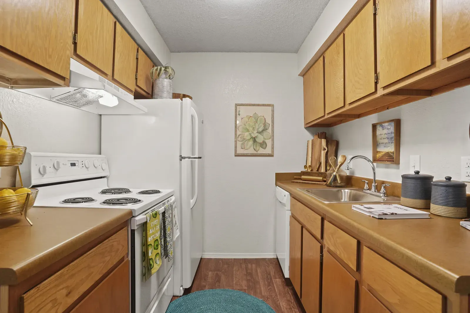 View of a modern kitchen with wooden cabinets, white appliances, and decorative accents.