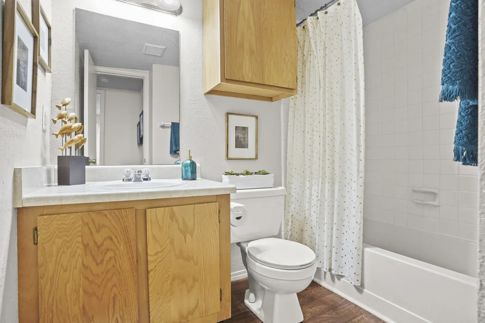 View of a bathroom featuring a sink, mirror, shower, and wooden cabinets.