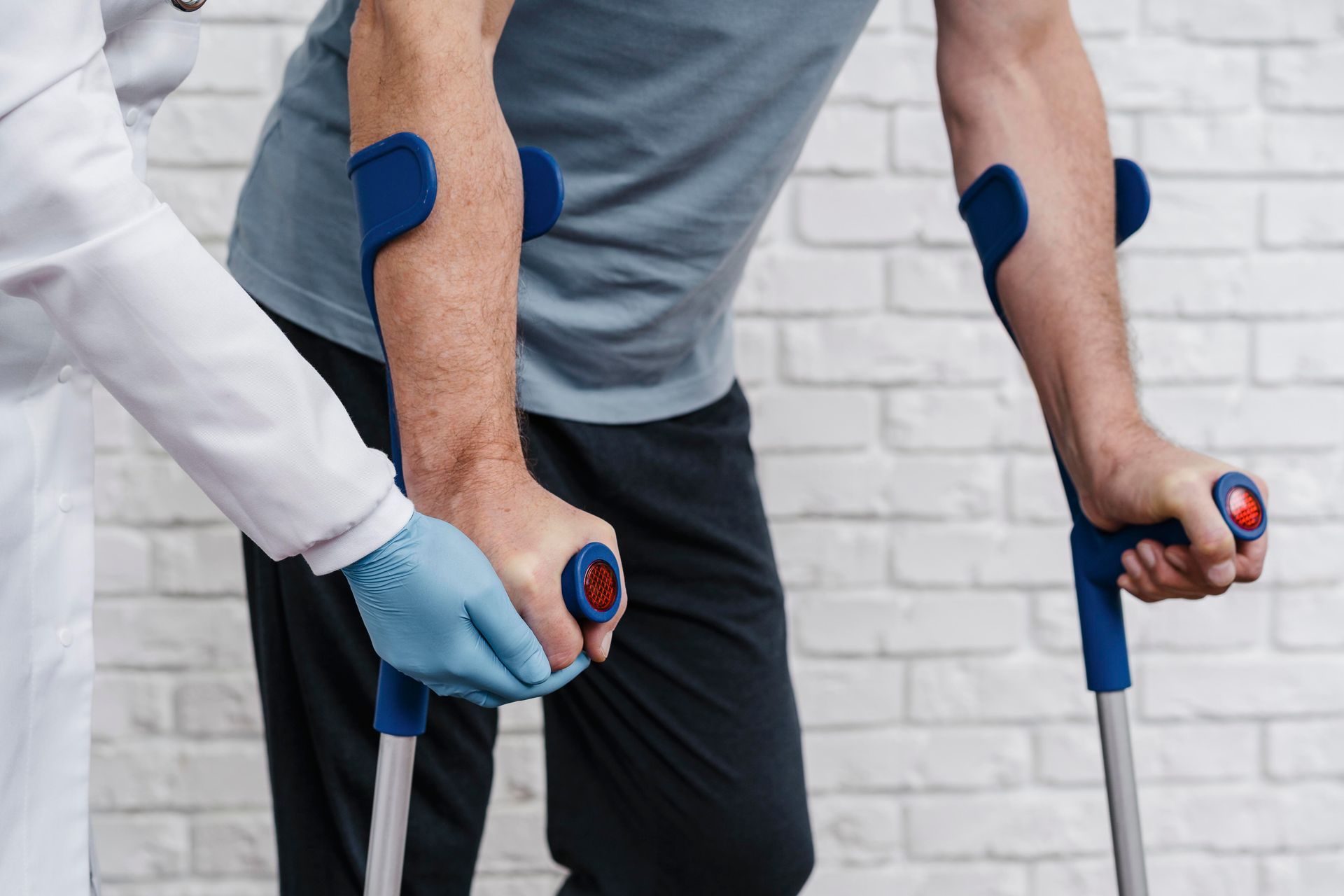 A man with crutches is being helped by a doctor.