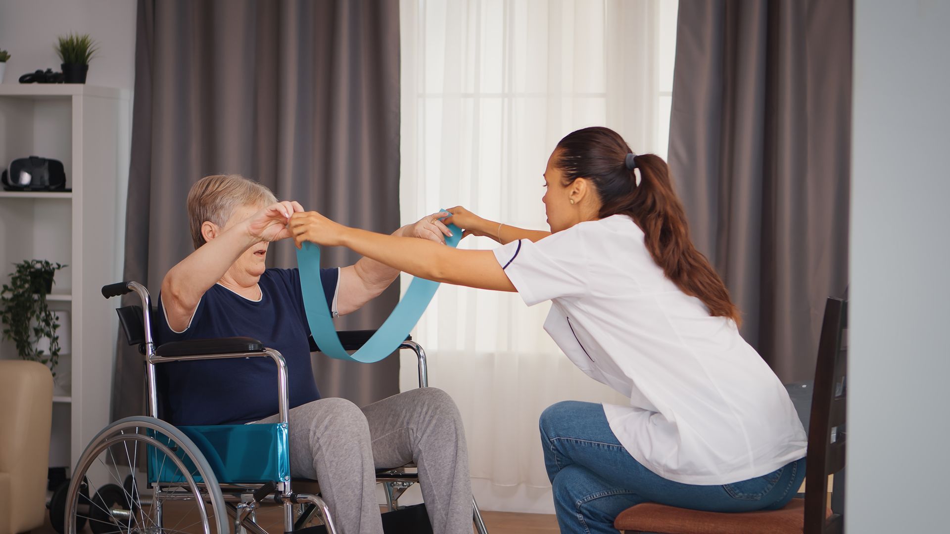 A nurse is helping an elderly woman in a wheelchair with a ribbon.