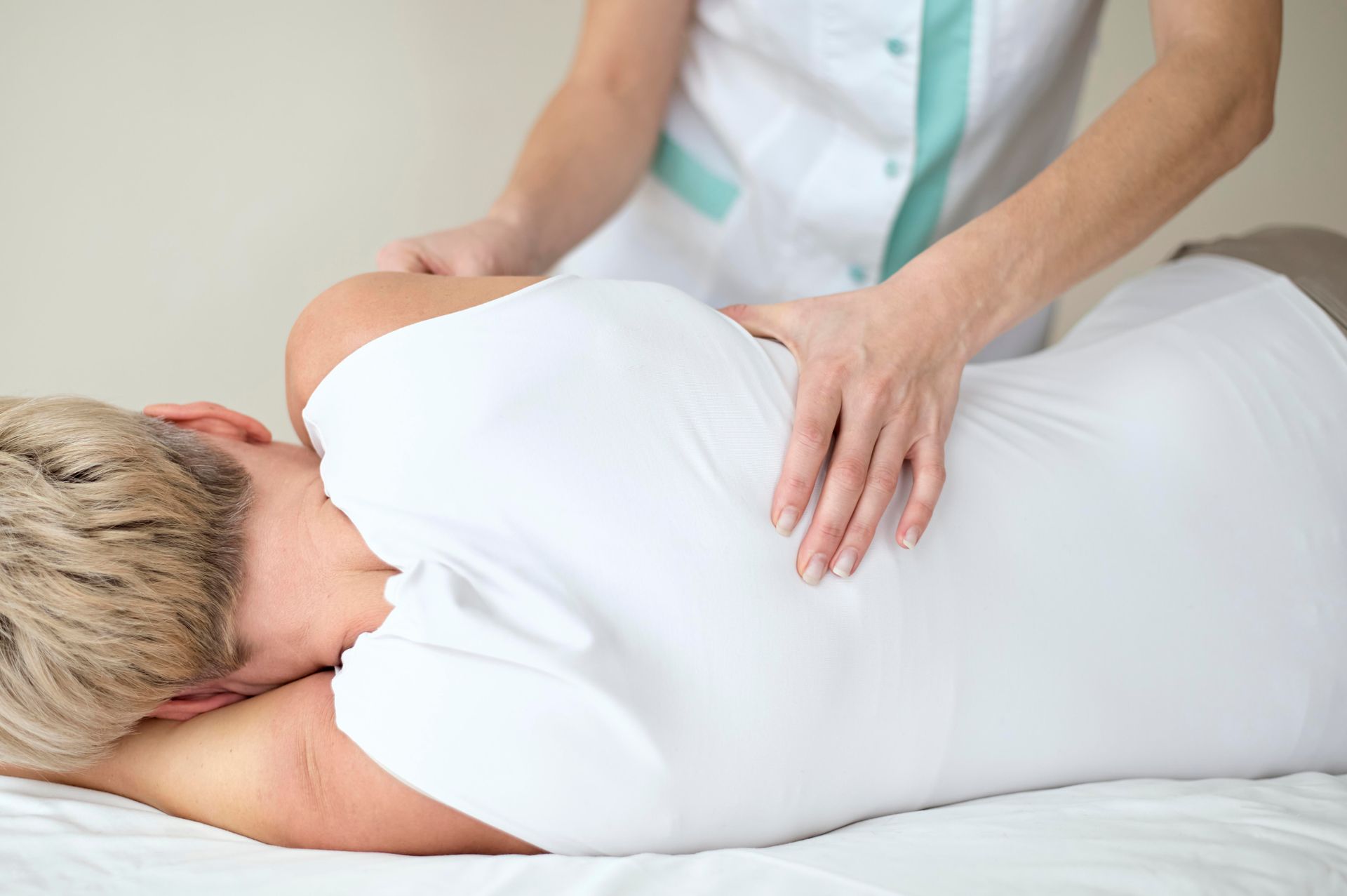 A woman is laying on a bed getting a massage from a doctor.