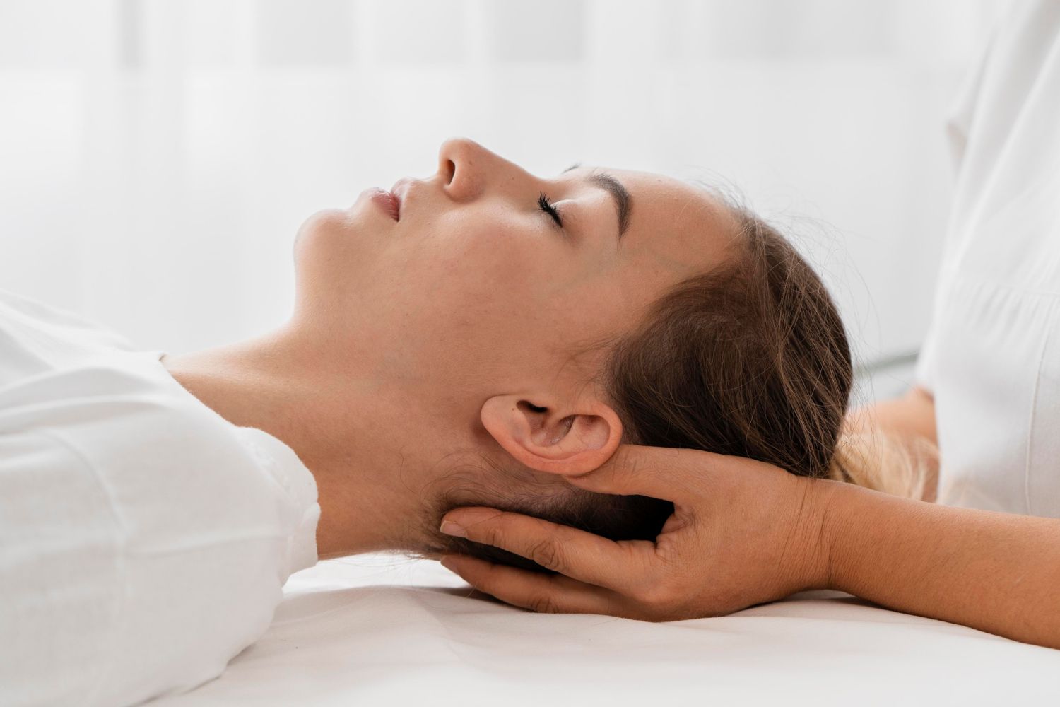Person receiving neck massage; hands on head, eyes closed.