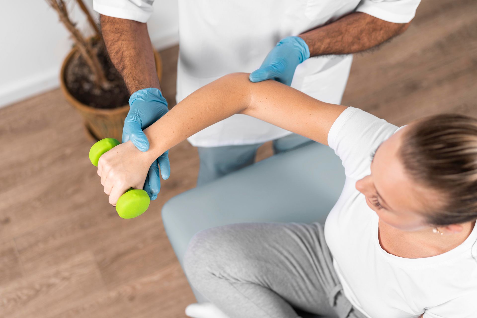 A woman is holding a green dumbbell in her hand.