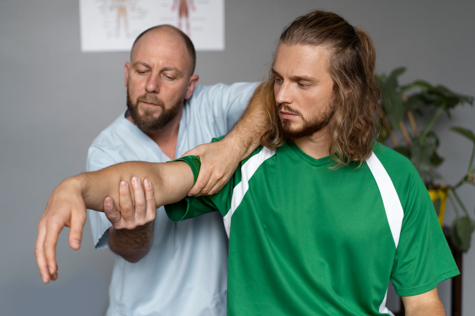 A man in a green shirt is getting his arm examined by a doctor.