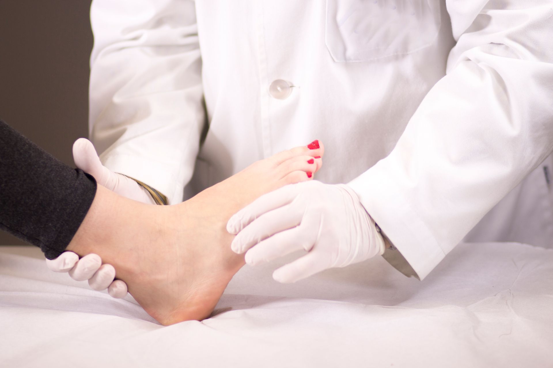 A doctor is examining a patient 's foot on a bed.