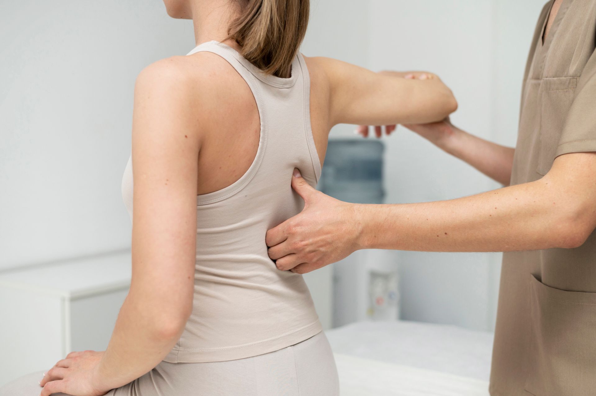 A woman is sitting on a table getting a massage from a nurse.