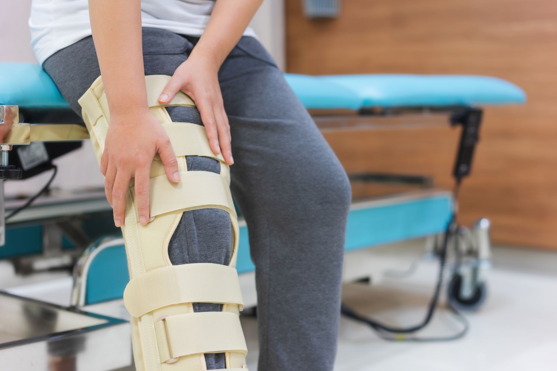 A woman is sitting on a bench with a knee brace on her leg.