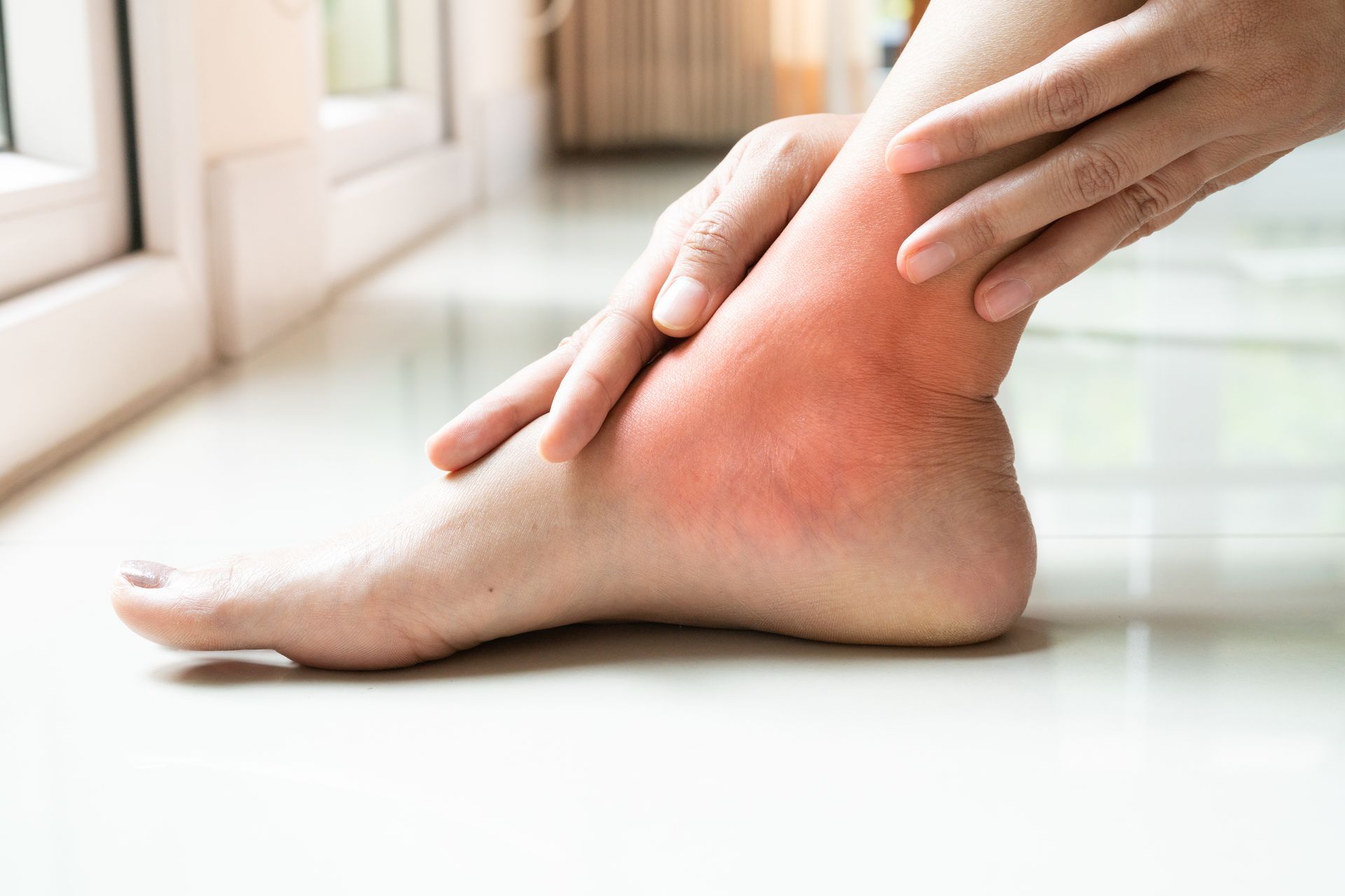 A person is holding their ankle in pain.