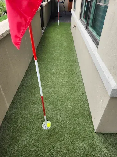 A putting green with a red flag and a golf ball on it.