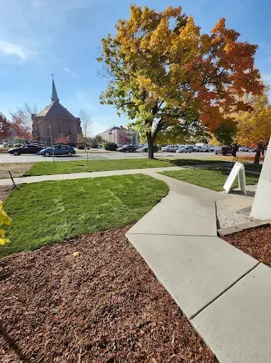 A sidewalk in a park with a church in the background.
