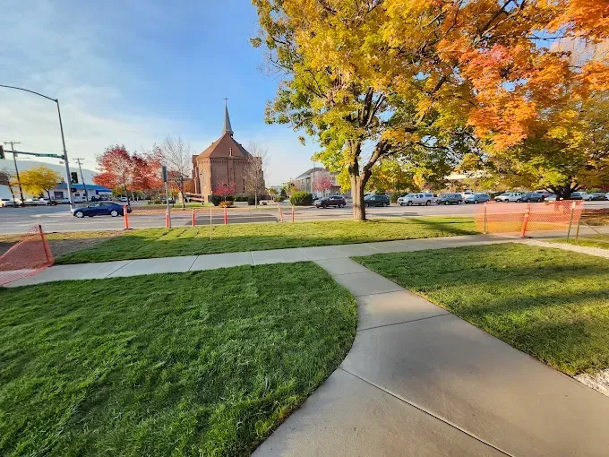 There is a church in the background and a sidewalk in the foreground.
