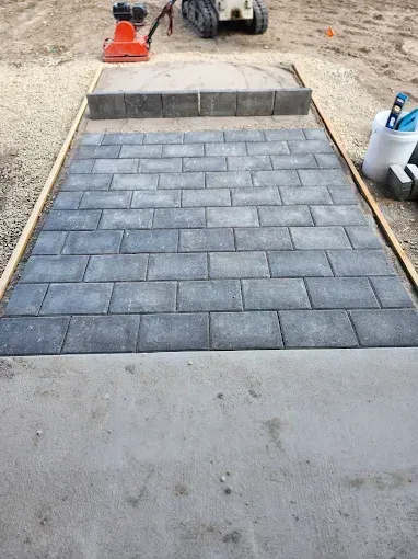 A brick walkway is being built next to a concrete walkway.