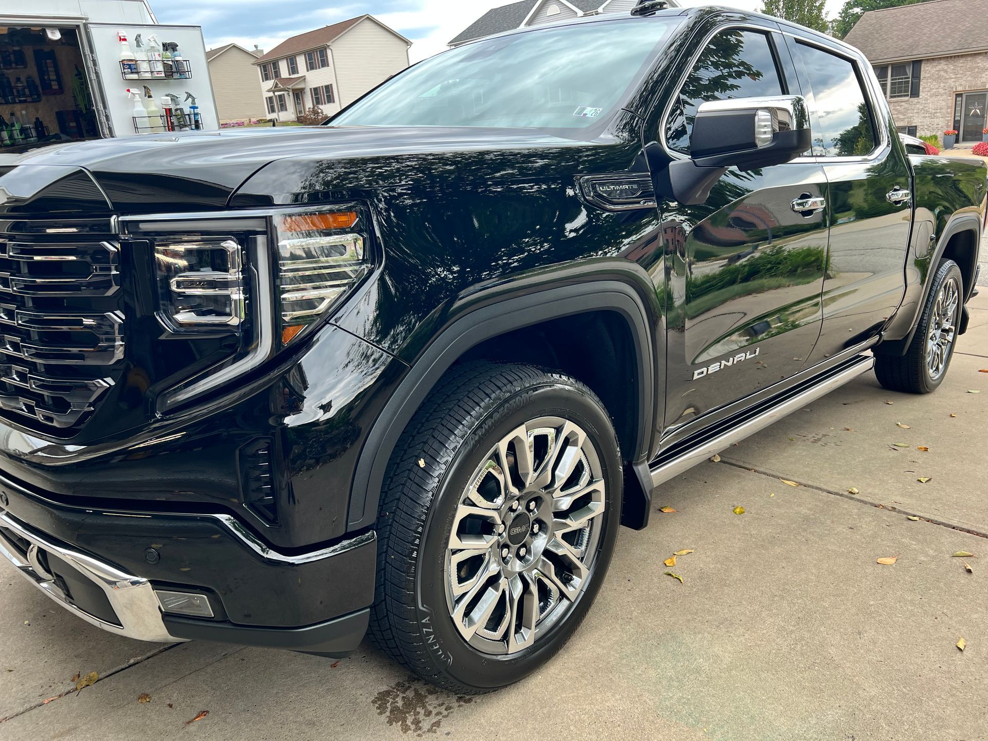 Black GMC Sierra truck parked on a driveway, shiny chrome wheels, and tinted windows.