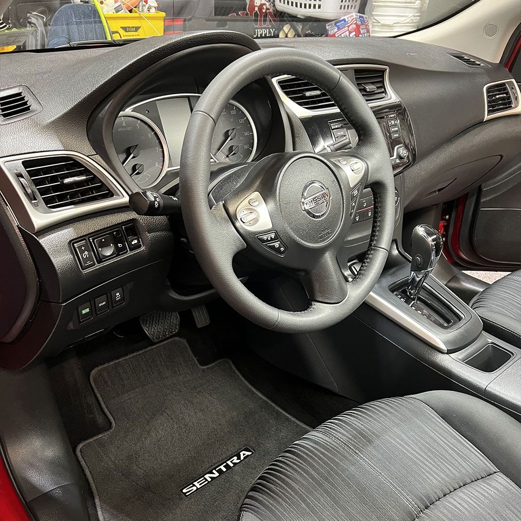 Interior of a Nissan Sentra car, black and gray dashboard, steering wheel, and seats.