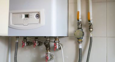Wall-mounted boiler with pipes and valves in a tiled utility room