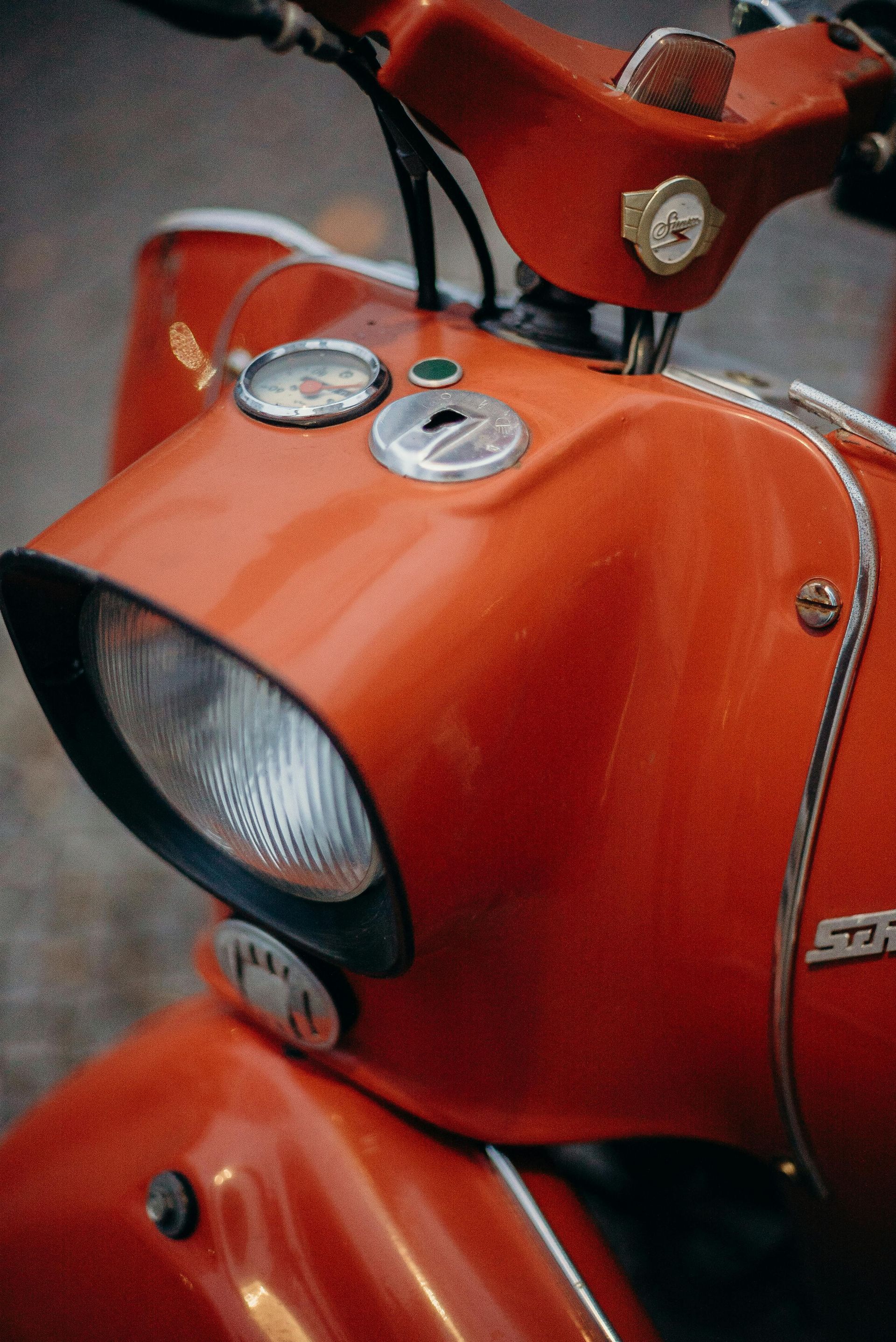 A close up of a red motorcycle with a clock on the handlebars.