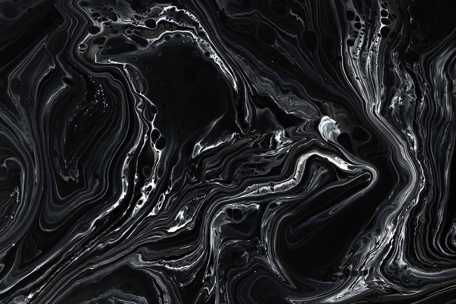Abstract swirling black and white pattern resembling marble or liquid, with fluid lines.