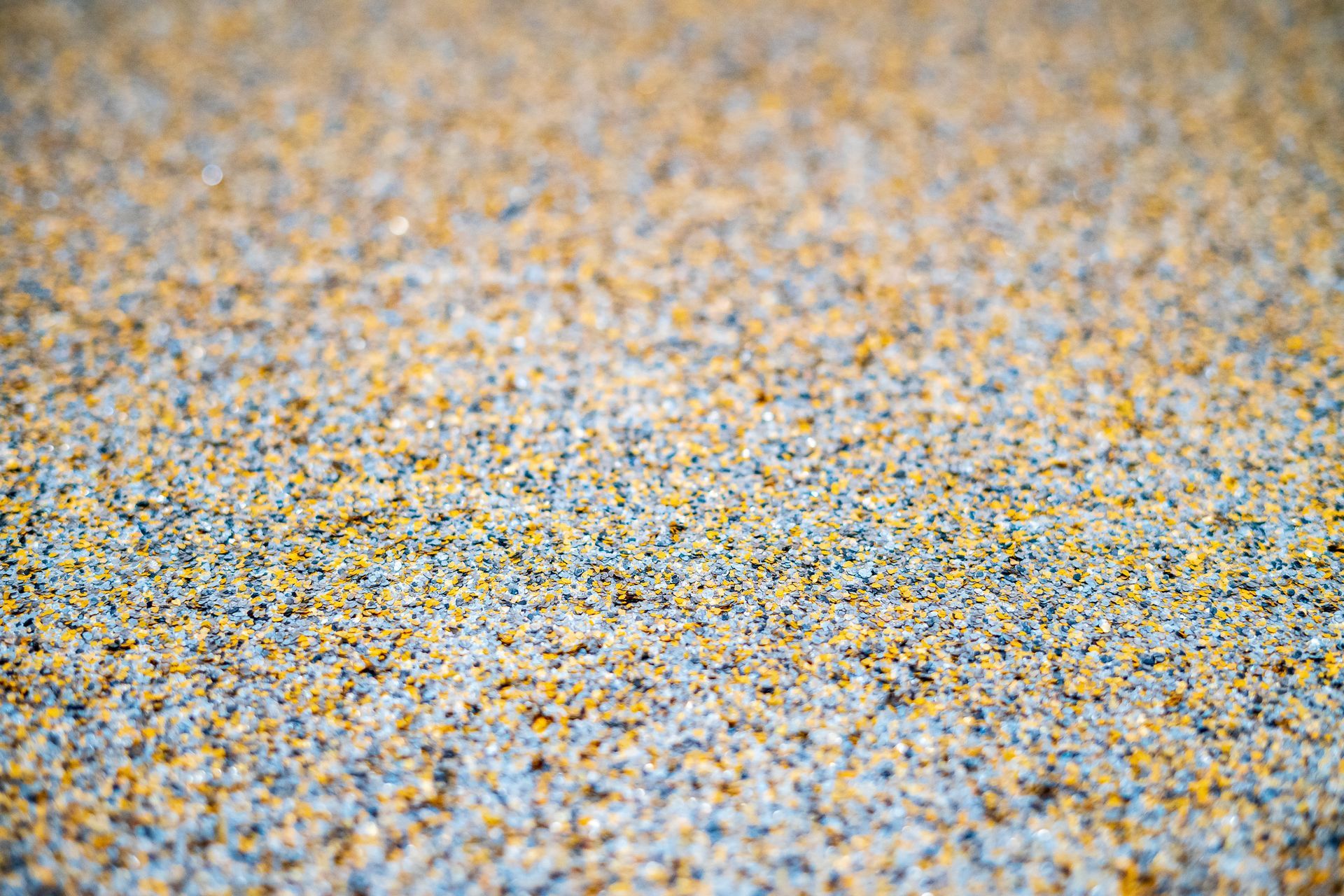 Close-up of a speckled, textured surface with blue, yellow, and gray grains.