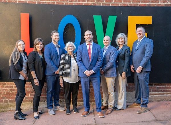 A man with a backpack is standing next to a lake in the woods.