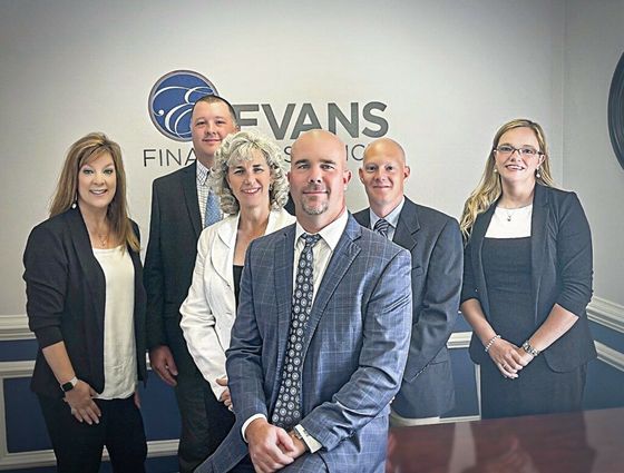 A man with a backpack is standing next to a lake in the woods.