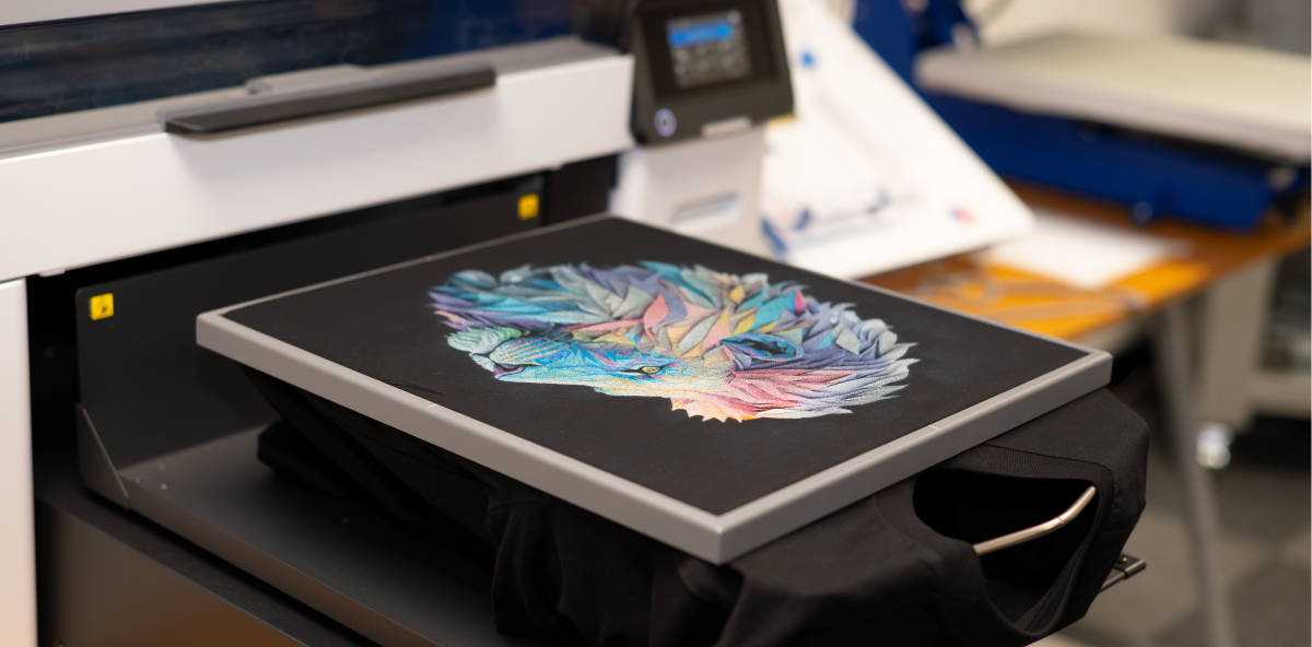 A machine is printing a picture on to a black t-shirt.