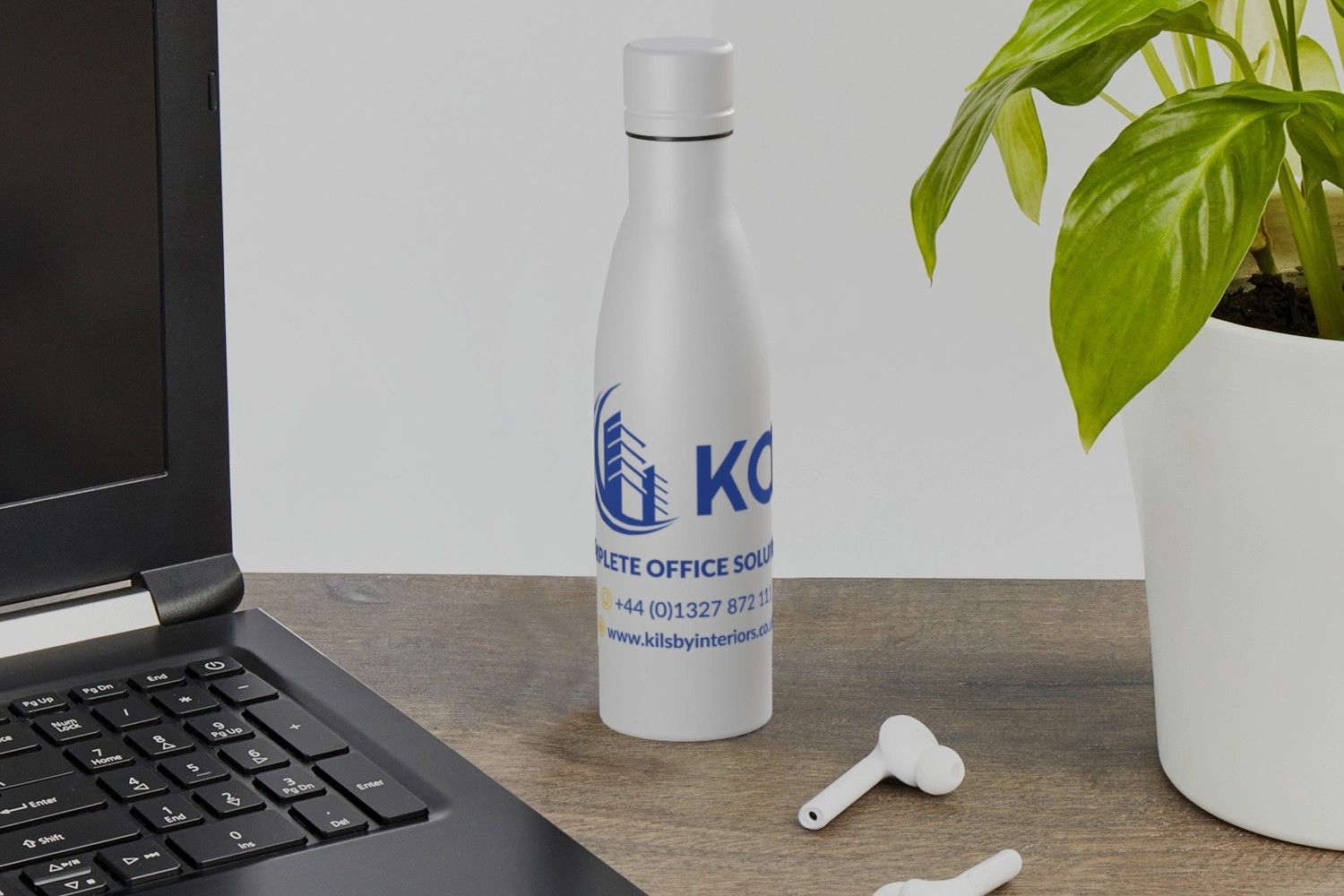 A water bottle is sitting on a desk next to a laptop and a plant.