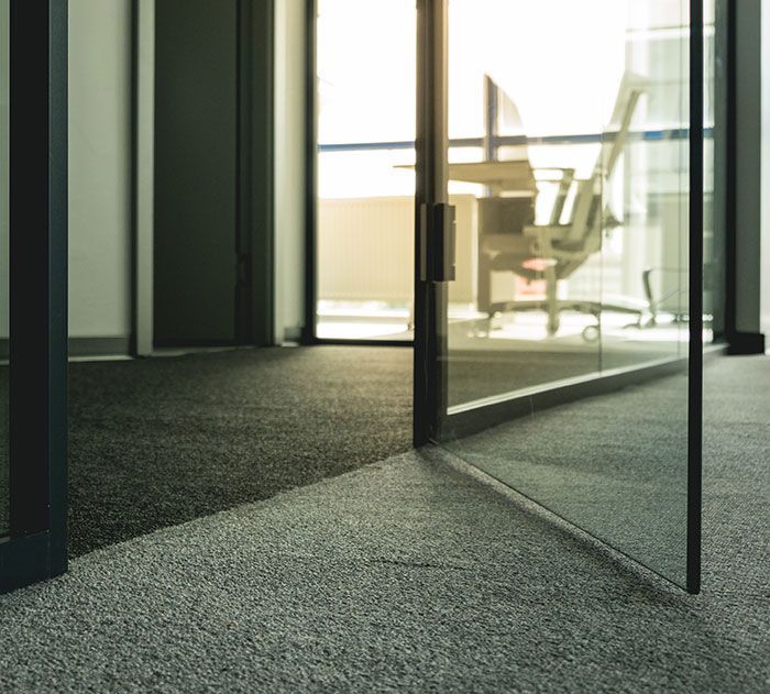 A room with a glass door and a chair in the background.