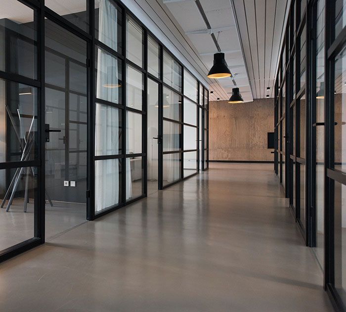 A long hallway with a lot of windows and lamps hanging from the ceiling.