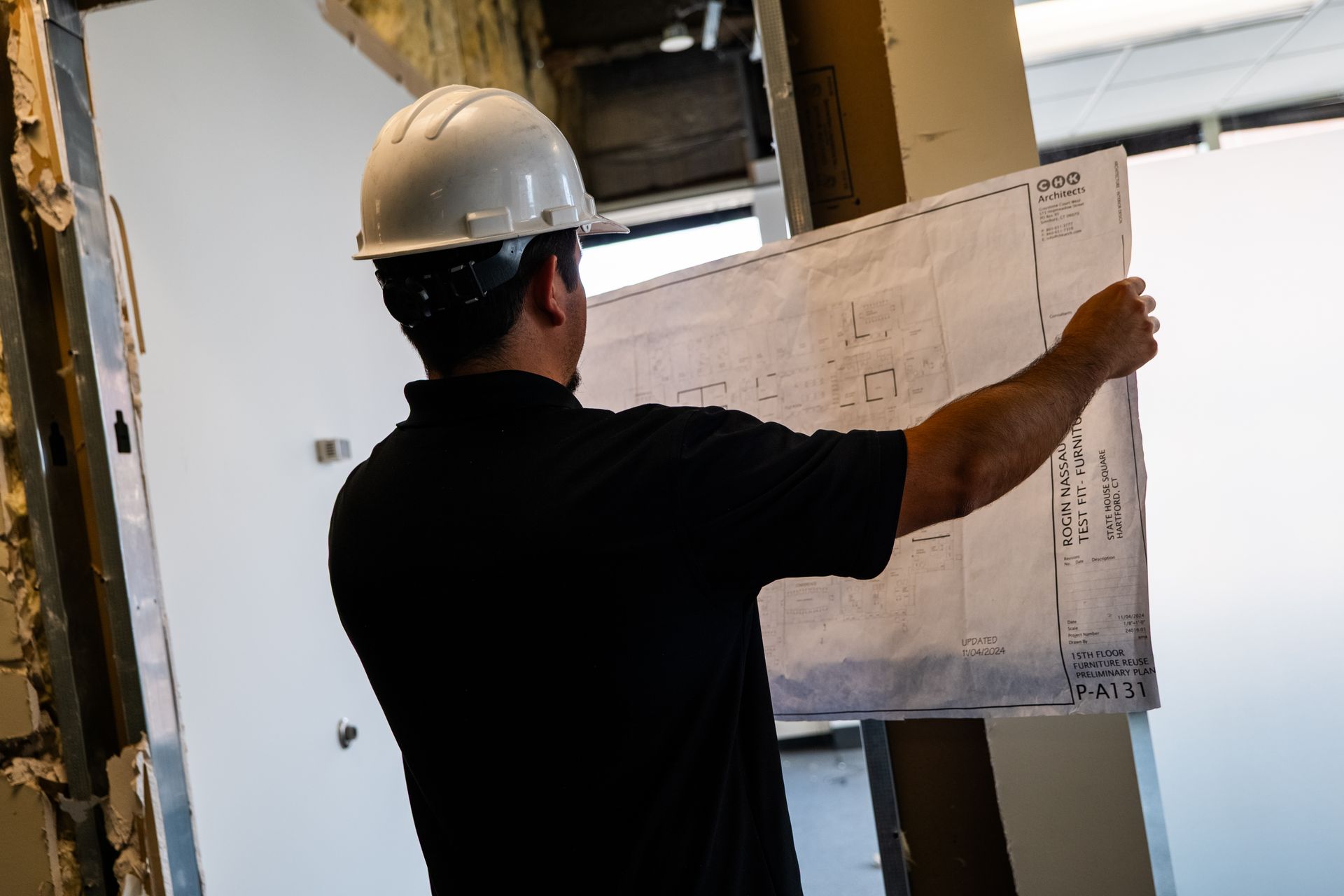 A construction worker is standing in front of a building under construction.