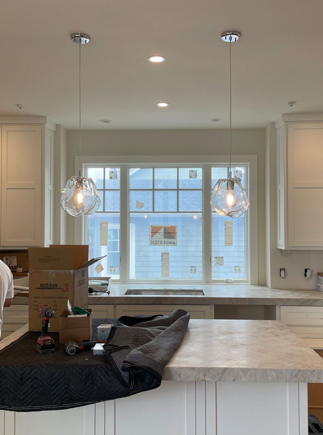 A kitchen with white cabinets and a large window.
