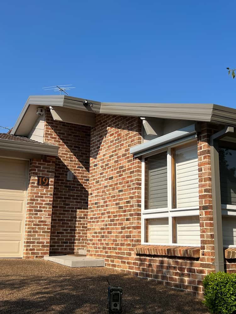 A Brick House With a Garage and a Blue Sky in the Background — DC Roofing In Eastwood, NSW