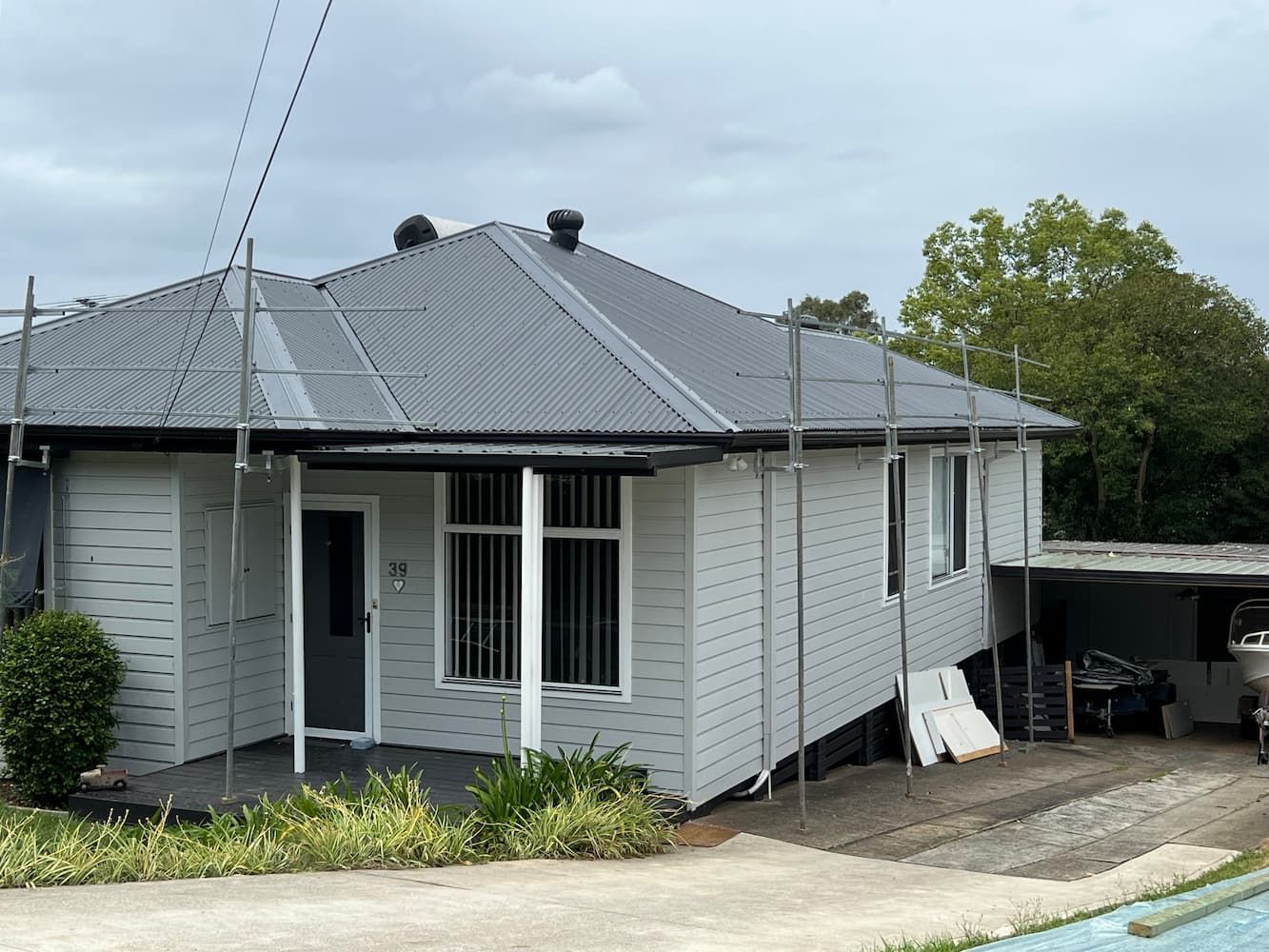A White House With a Gray Roof is Being Remodeled — DC Roofing In Marsden Park, NSW