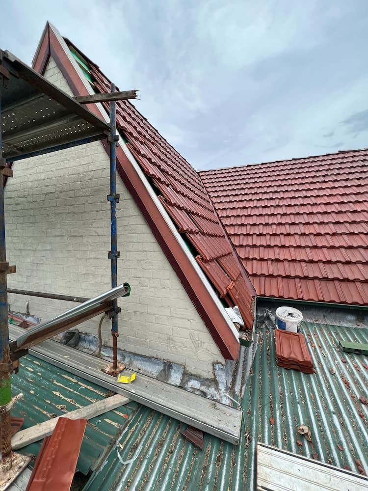A Red Tiled Roof is Being Installed on a Building — DC Roofing In Marsden Park, NSW