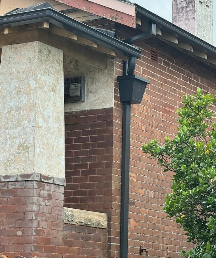 A Brick Building With a Black Gutter on the Side of It — DC Roofing In Marsden Park, NSW