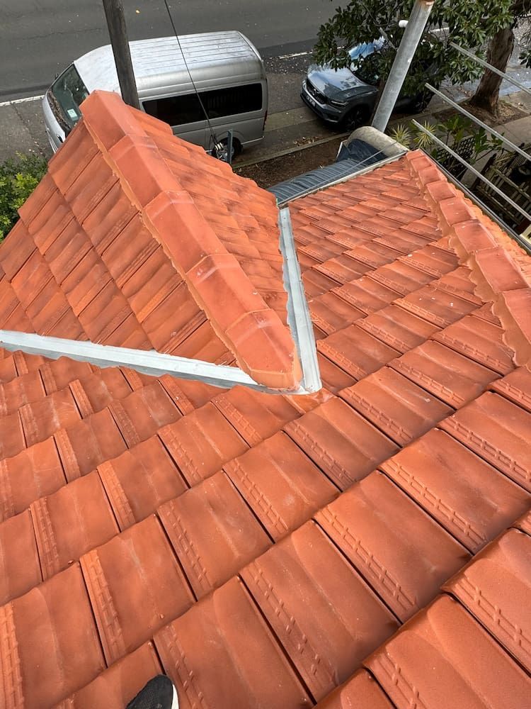 A Red Tiled Roof With a White Van Parked in the Background — DC Roofing In Marsden Park, NSW