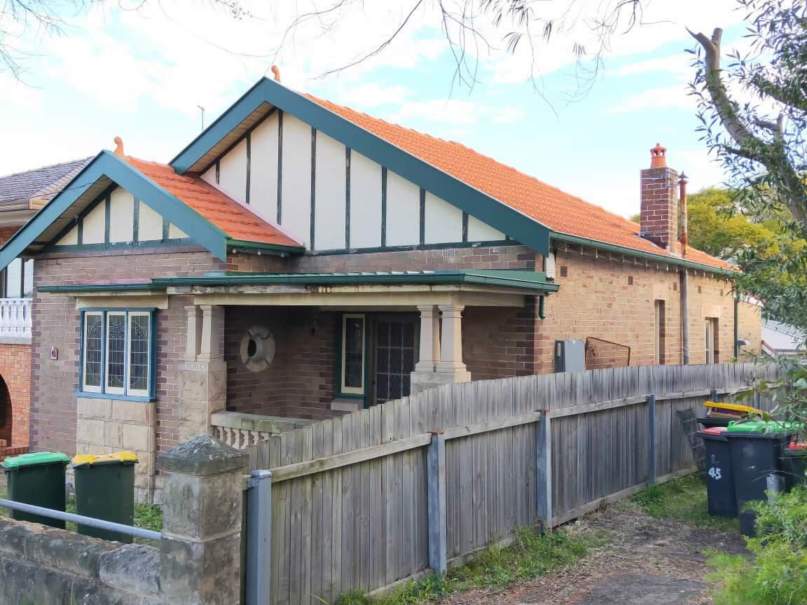 A Brick House With a Wooden Fence Around It — DC Roofing In Marsden Park, NSW
