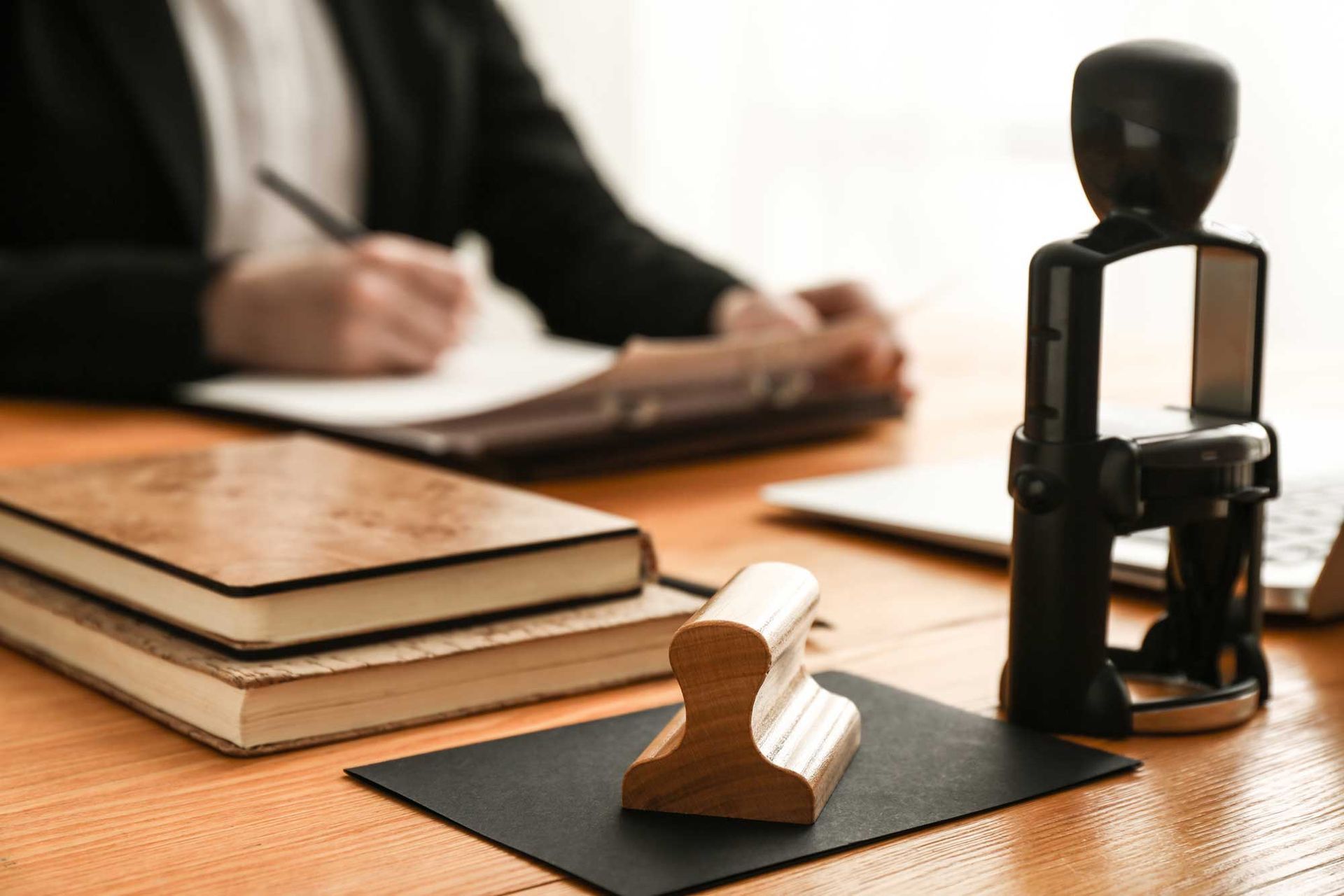 Books and stamps on a table of a lawyer as he writes in the background.